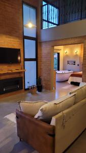 a large living room with a couch and a tv at Casa Chalé dos Pinhas - Chalé Romântico e Aconchegante - Hidromassagem - Lareira - Vista da Montanha - Próximo a Campos do Jordão in Santo Antônio do Pinhal