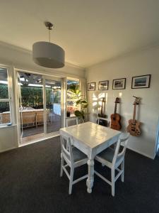 a dining room with a table and two guitars on the wall at Sunbeam Cottage in Havelock North