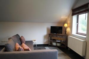 a living room with a couch and a flat screen tv at Guesthouse Biolleke in Boutersem