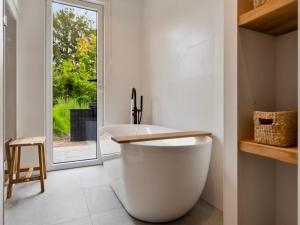 a bathroom with a large white tub and a window at Het Duinnest in Kamperland +22 photos