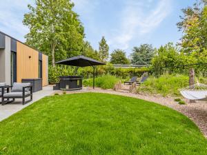 a backyard with a lawn with a grill and an umbrella at Het Duinnest in Kamperland