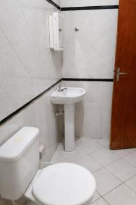a white bathroom with a toilet and a sink at Pousada Quixadá Confort in Quixadá