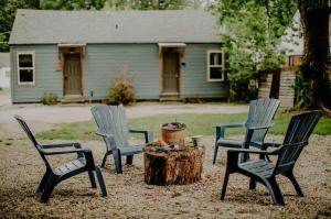 three chairs and a tree stump in front of a house at Urban Airstream Retreat in Memphis