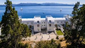 a white building with people walking in front of the water at B612 Bariloche in San Carlos de Bariloche
