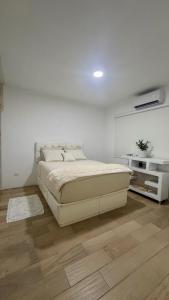 a white bedroom with a bed and a wooden floor at Casa Costa Hermosa in Tijuana