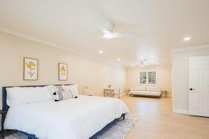 a bedroom with a white bed with a ceiling fan at Casteel - 4,500 sq-ft retreat with a pool and hot tub in the middle of wine country! in Templeton +41 photos