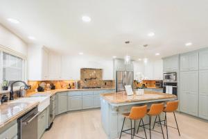a large kitchen with blue cabinets and orange bar stools at Casteel - 4,500 sq-ft retreat with a pool and hot tub in the middle of wine country! in Templeton