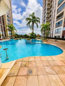 a large blue swimming pool with palm trees and buildings at Apartamento perto do aeroporto e do estádio do mangueirão in Belém
