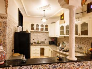 a kitchen with white cabinets and a black refrigerator at Appartement Riad à Taroudant Piscine Privée & Grand Jardin, Séjour Unique in Taroudant