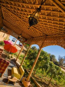 an umbrella and a chair under a straw roof at Appartement Riad à Taroudant Piscine Privée & Grand Jardin, Séjour Unique in Taroudant