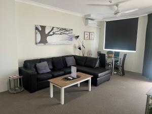 a living room with a black leather couch and a table at Serenity in Surfers Paradise in Gold Coast