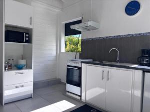 a kitchen with white cabinets and a sink and a stove at Eco-Nature Studio in Petit-Canal