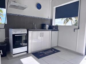 a kitchen with white cabinets and a stove top oven at Eco-Nature Studio in Petit-Canal +4 photos