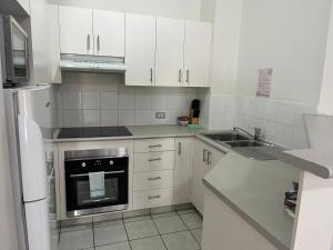 a small kitchen with white cabinets and a sink at Serenity in Surfers Paradise in Gold Coast