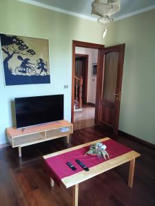 a living room with a tv and a table at Casa Vicino in Carrù