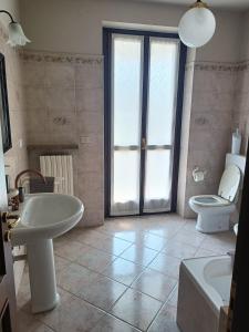 a bathroom with a white sink and a toilet at Casa Vicino in Carrù +30 photos