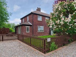 a brick house with a fence and a tree at 3 Bed in York oc-hh015 in Tockwith