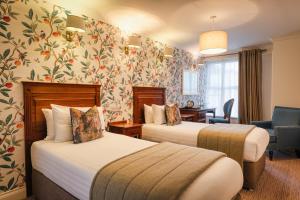 zwei Betten in einem Hotelzimmer mit Blumentapete in der Unterkunft Castle Hotel in Dublin