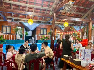 a group of people sitting at tables in a restaurant at Retreat Bungalow in Phong Nha