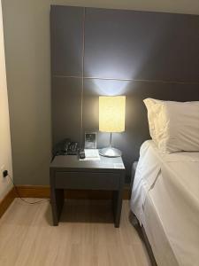 a bedroom with a desk with a bed and a lamp at Araucária Flat Apto 305 in Ribeirão Preto