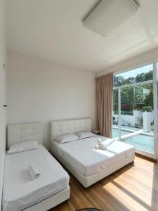two beds in a bedroom with a large window at Penang Gelugor Landed House 4Rooms 3 Bathrooms in Gelugor