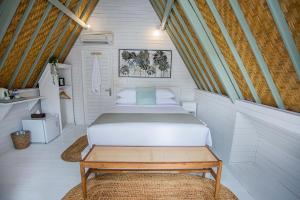 a bedroom with a bed and a bench in it at D'Yuki Huts Lembongan in Nusa Lembongan +64 photos