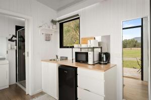 a kitchen with a counter with a microwave and a window at Halls Haven Tiny House 1 by Tiny Away in Halls Gap +20 photos