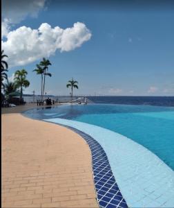 a swimming pool next to a beach with palm trees at Tropical Executive Hotel in Manaus