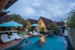 a pool at a resort with chairs and umbrellas at D'Yuki Huts Lembongan in Nusa Lembongan