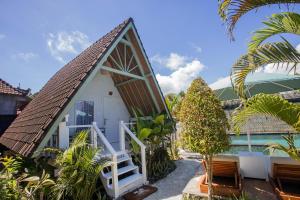 a small white house with a steep roof at D'Yuki Huts Lembongan in Nusa Lembongan