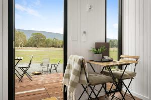 a porch with a table and chairs and a view of a field at Halls Haven Tiny House 2 by Tiny Away in Halls Gap
