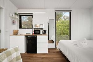 a bedroom with a bed and a kitchen with a microwave at Halls Haven Tiny House 2 by Tiny Away in Halls Gap