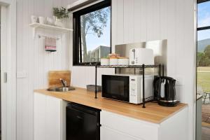 a kitchen with a counter with a microwave and a sink at Halls Haven Tiny House 2 by Tiny Away in Halls Gap