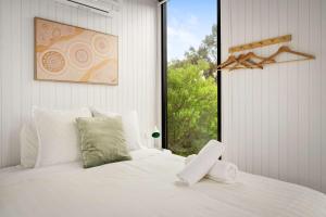 a bedroom with a white bed with a window at Halls Haven Tiny House 2 by Tiny Away in Halls Gap +19 photos