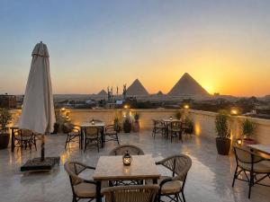 a patio with tables and chairs with pyramids in the background at Arte Pyramids Hotel in Cairo