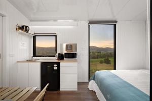 a bedroom with a bed and a kitchen with a microwave at Nichol Road Hideaway at Annies Retreat by Tiny Away in Yackandandah