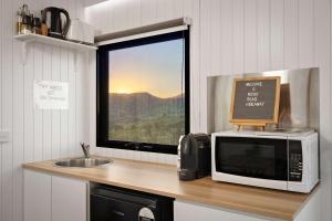 a kitchen with a microwave and a sink and a window at Nichol Road Hideaway at Annies Retreat by Tiny Away in Yackandandah