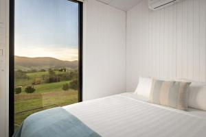 a bedroom with a bed and a large window at Nichol Road Hideaway at Annies Retreat by Tiny Away in Yackandandah