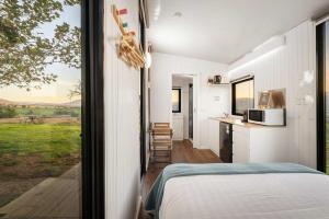 a bedroom with a bed and a large window at Nichol Road Hideaway at Annies Retreat by Tiny Away in Yackandandah