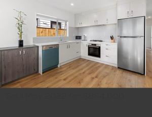 a kitchen with white cabinets and a stainless steel refrigerator at 1 Spacious bedroom available in Auckland