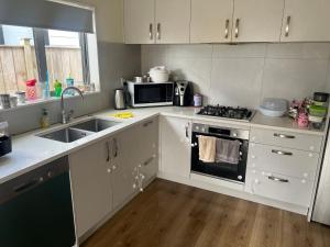 a kitchen with white cabinets and a sink and a microwave at 1 Spacious bedroom available in Auckland +2 photos