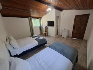 a bedroom with two beds and a television in it at Pousada Colibris da Barra da Tijuca in Rio de Janeiro
