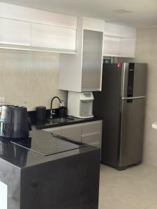 a kitchen with a black refrigerator and white cabinets at Studio 404 Premium Flat - Juazeiro do Norte - Cariri in Juazeiro do Norte