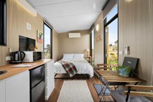 a bedroom with a bed and a desk and a kitchen at Tiny Regen Farm Stay by Tiny Away in Lawrence