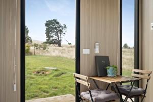 a room with a table and chairs with a view of a field at Tiny Regen Farm Stay by Tiny Away in Lawrence