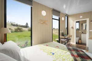 a bedroom with a large bed and a large window at Tiny Regen Farm Stay by Tiny Away in Lawrence