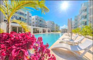 a swimming pool with two lounge chairs and a palm tree at Dominican paradise in Punta Cana