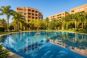 a large swimming pool with palm trees and buildings at Luxury Apartment with Private Jacuzzi & Pool Central Marrakech in Marrakesh