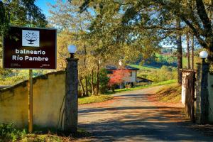 a sign for a country road with a house in the background at Hotel Balneario Río Pambre in Palas de Rei