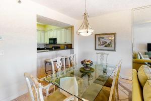 a dining room and kitchen with a glass table and chairs at TOPS'L Summit 1013 in Destin +15 photos